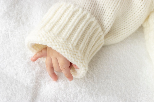 Baby's hand in white sweater
