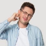 man in glasses touch ear